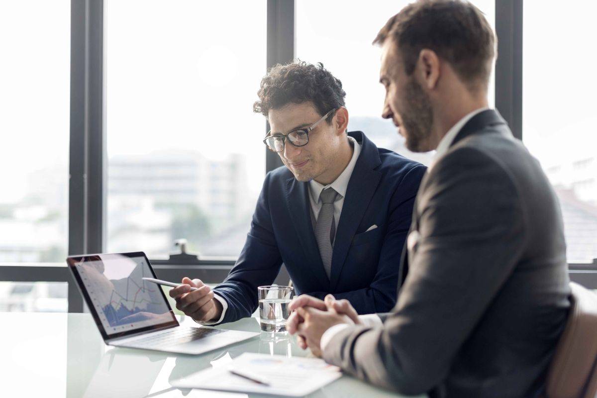 Two business professionals discussing data on a laptop during a meeting in a modern office