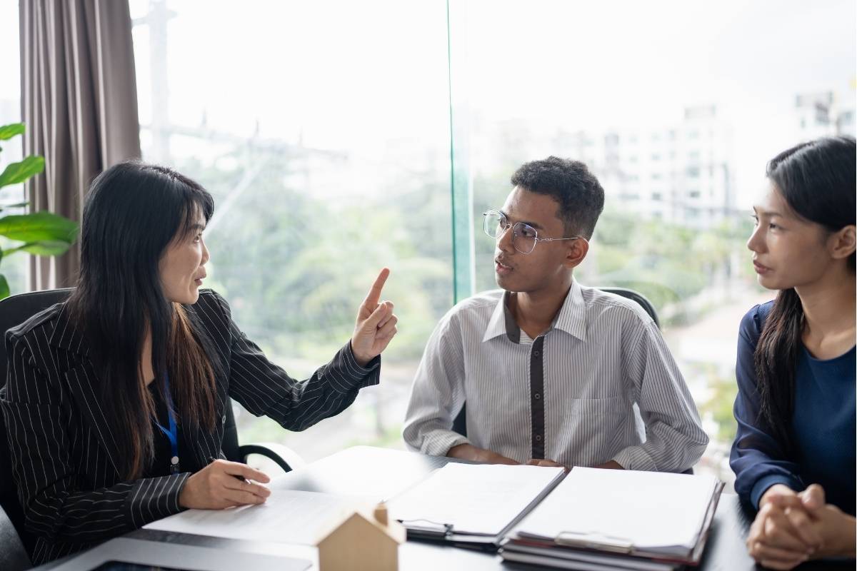 Consultant advising two clients in an office, discussing professional services and paperwork