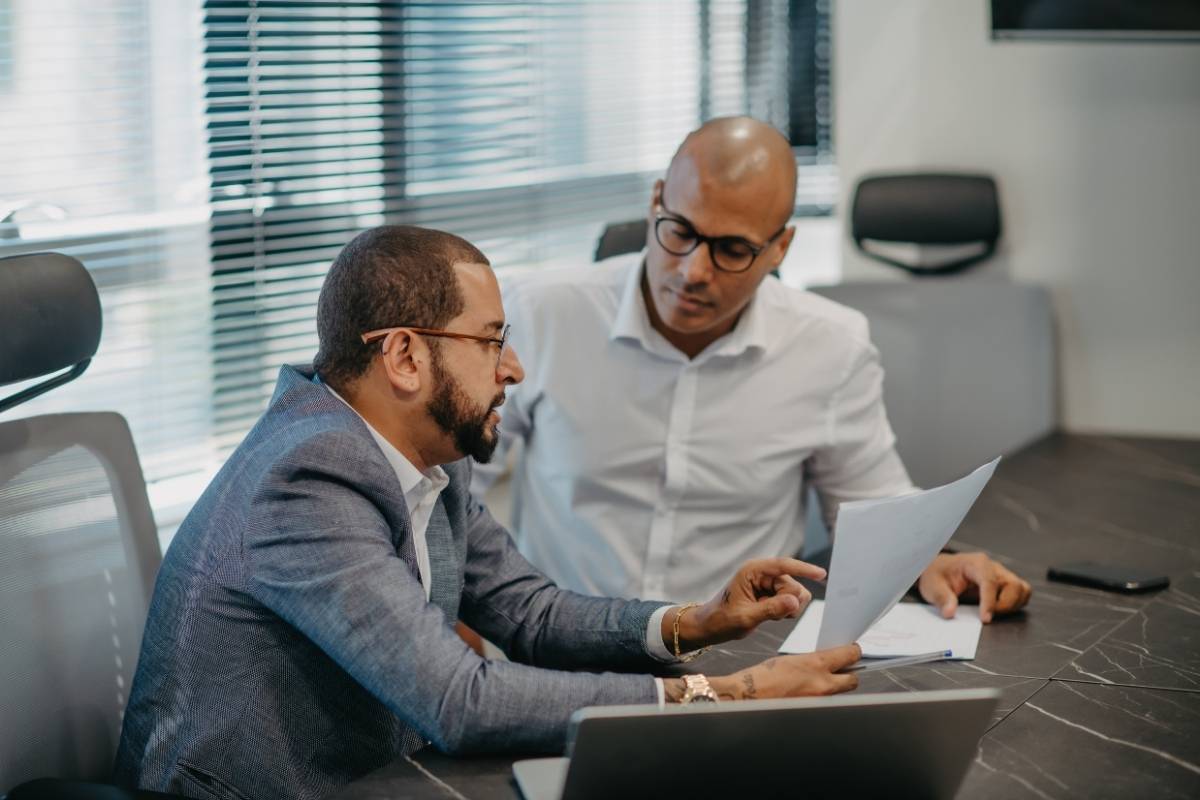 Consulting firm professionals in Sydney discussing business strategy, reviewing documents and data during a client meeting in a modern office.