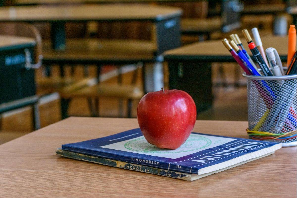 Education setting in Sydney classroom with books, pencils, and an apple on a teacher’s desk, symbolising learning and academic preparation.