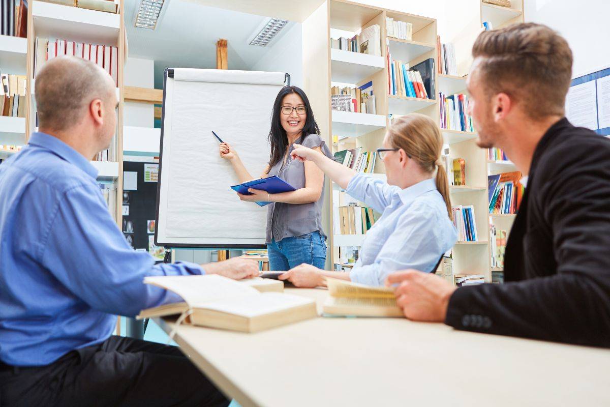 Teacher presenting on a whiteboard while students engage in a classroom discussion