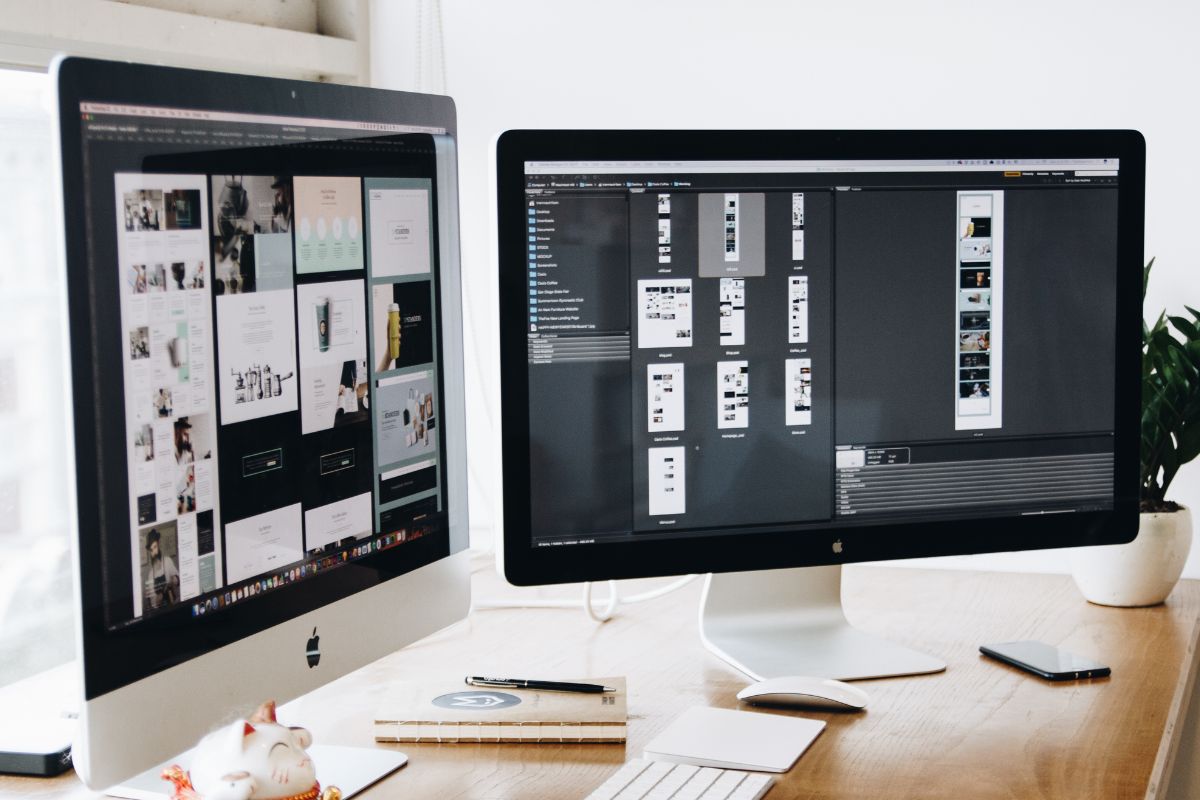 two computer monitors sitting on a wooden desk