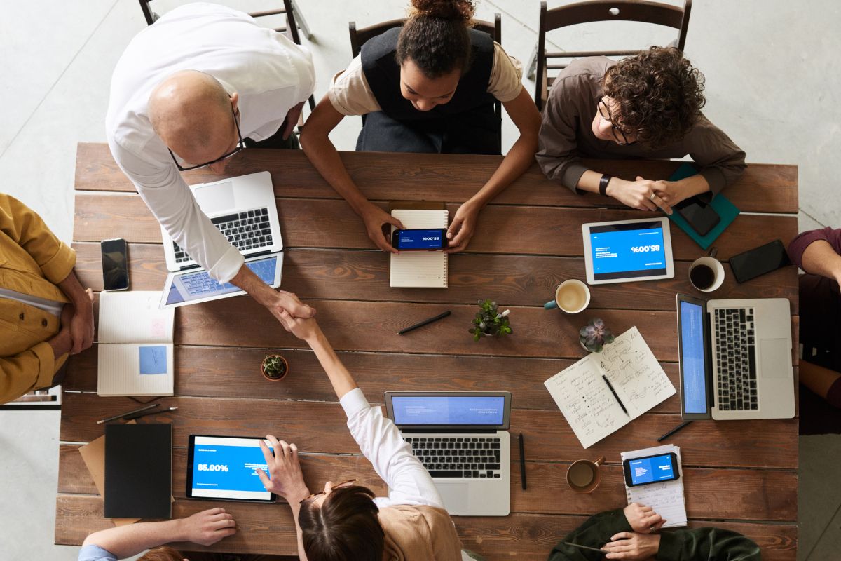 Team of professionals in Sydney collaborating during a strategy meeting, using laptops and tablets to discuss business services and digital projects.